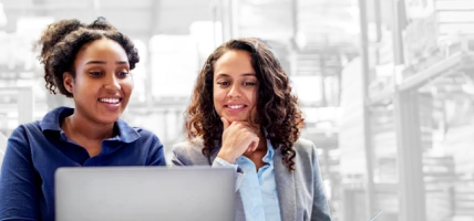 Two coworkers read info from a laptop.